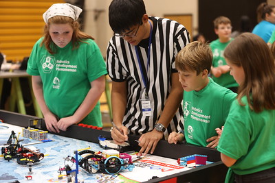 students placing a LEGO robot on the playing field