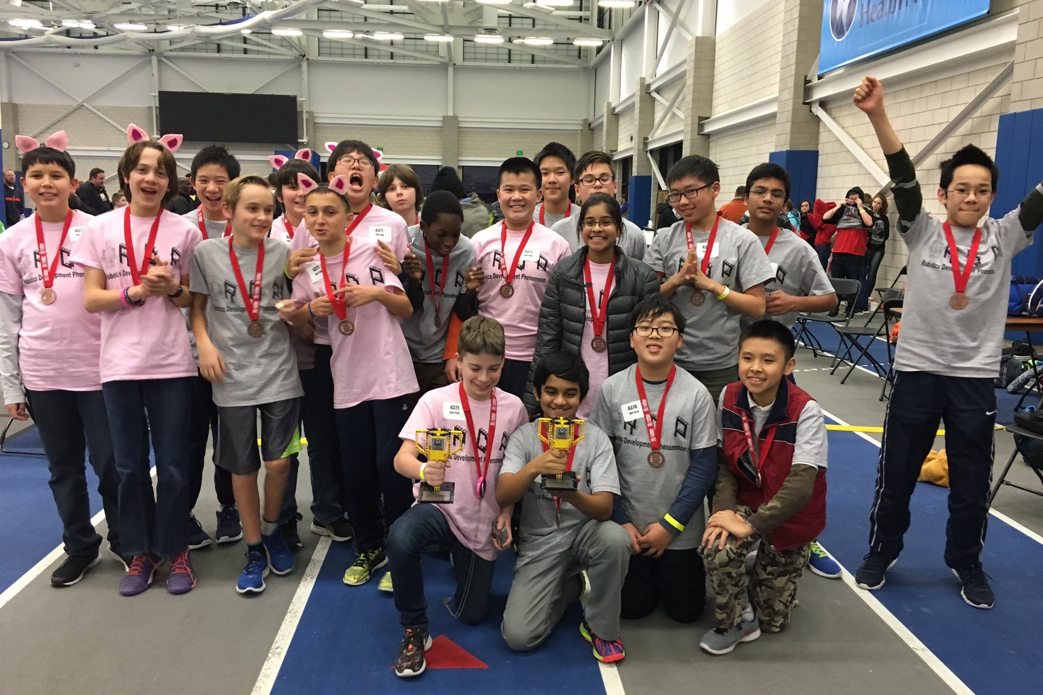 a group of happy students with medals and a trophy