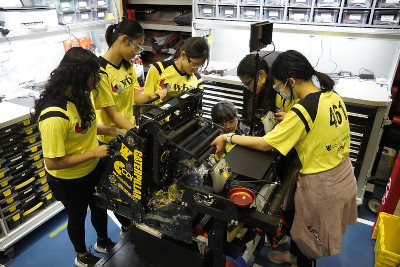 a group of girls working on the robot at a competition