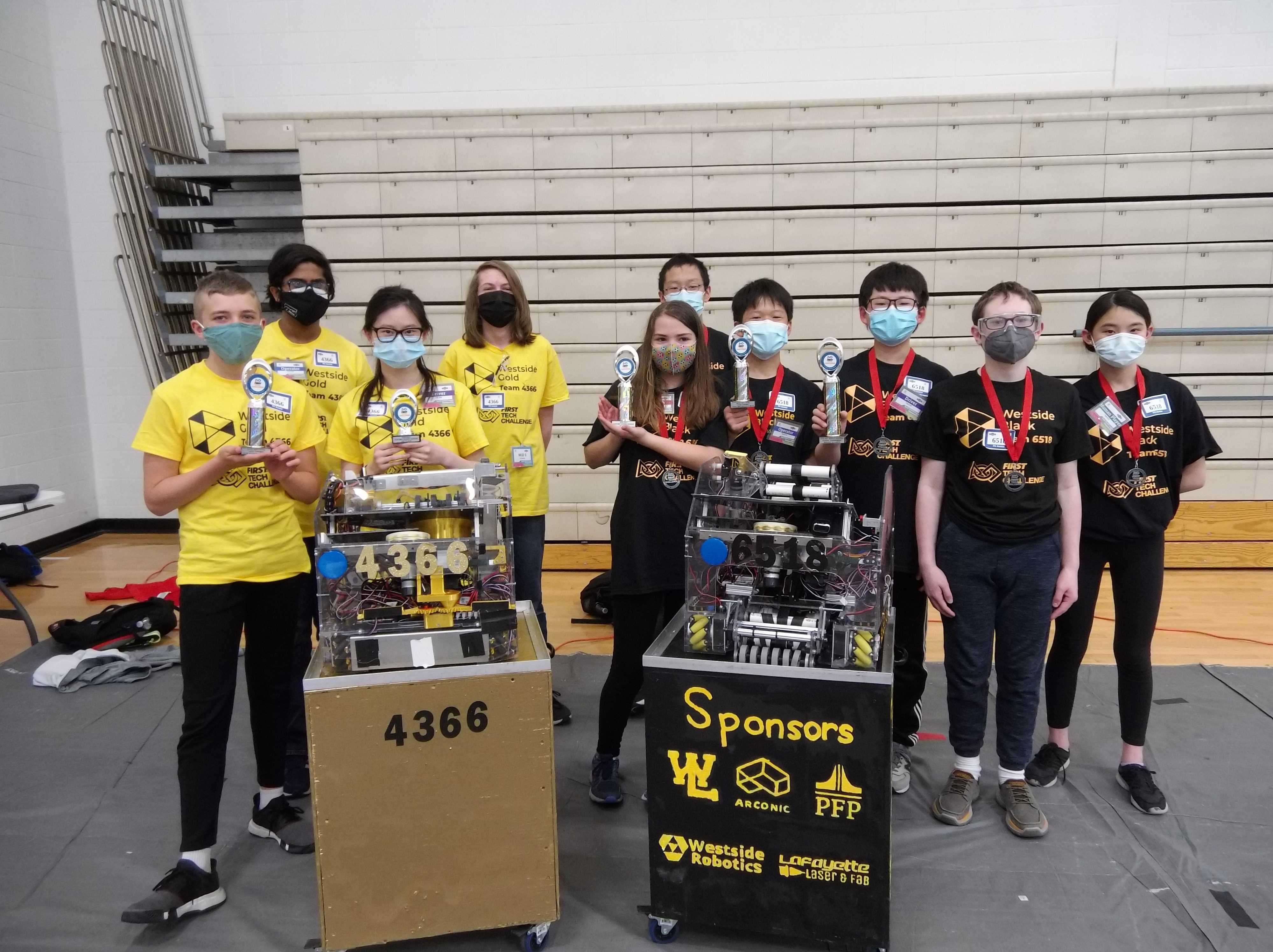 two groups of students posing with medals, trophies, and their robots